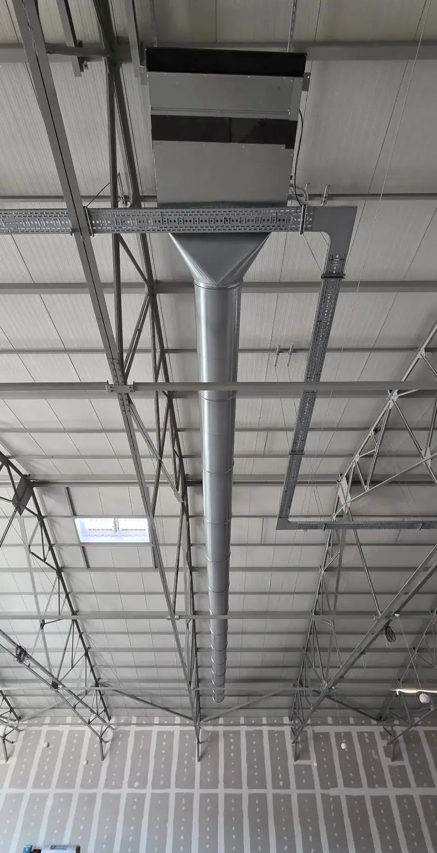 Gaine de ventilation tirée sous une charpente métallique